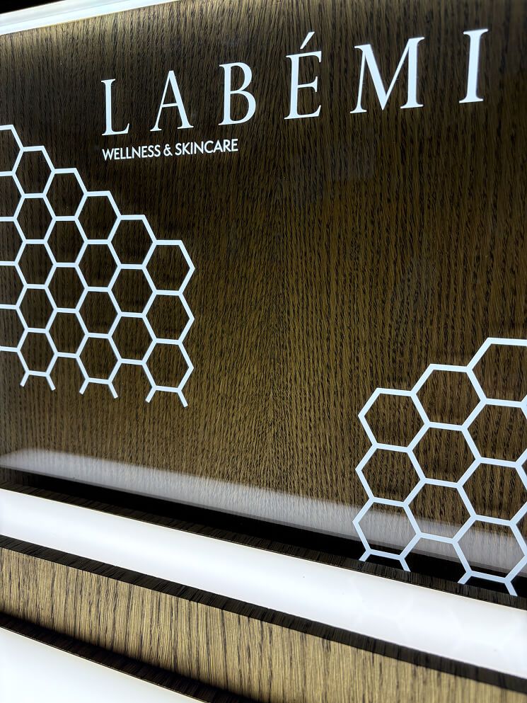 Detal logotypu LABÉMI na fornirze dębowym i podświetlonej krawędzi półki