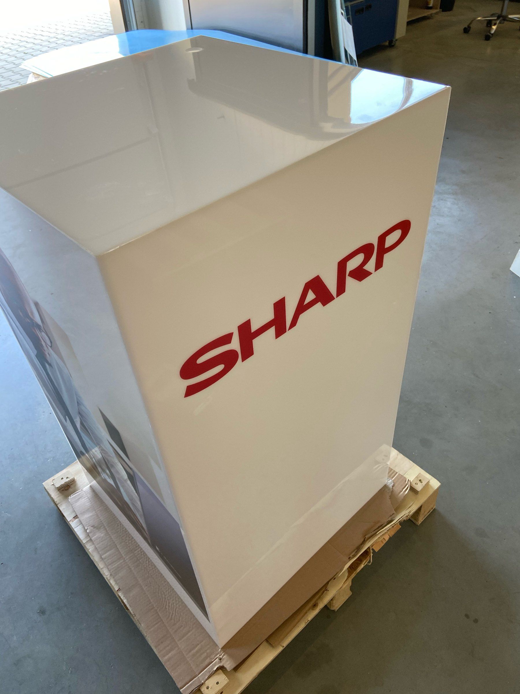 Kubik z logotypem Sharp na palecie w folii ochronnej przygotowany do wysyłki