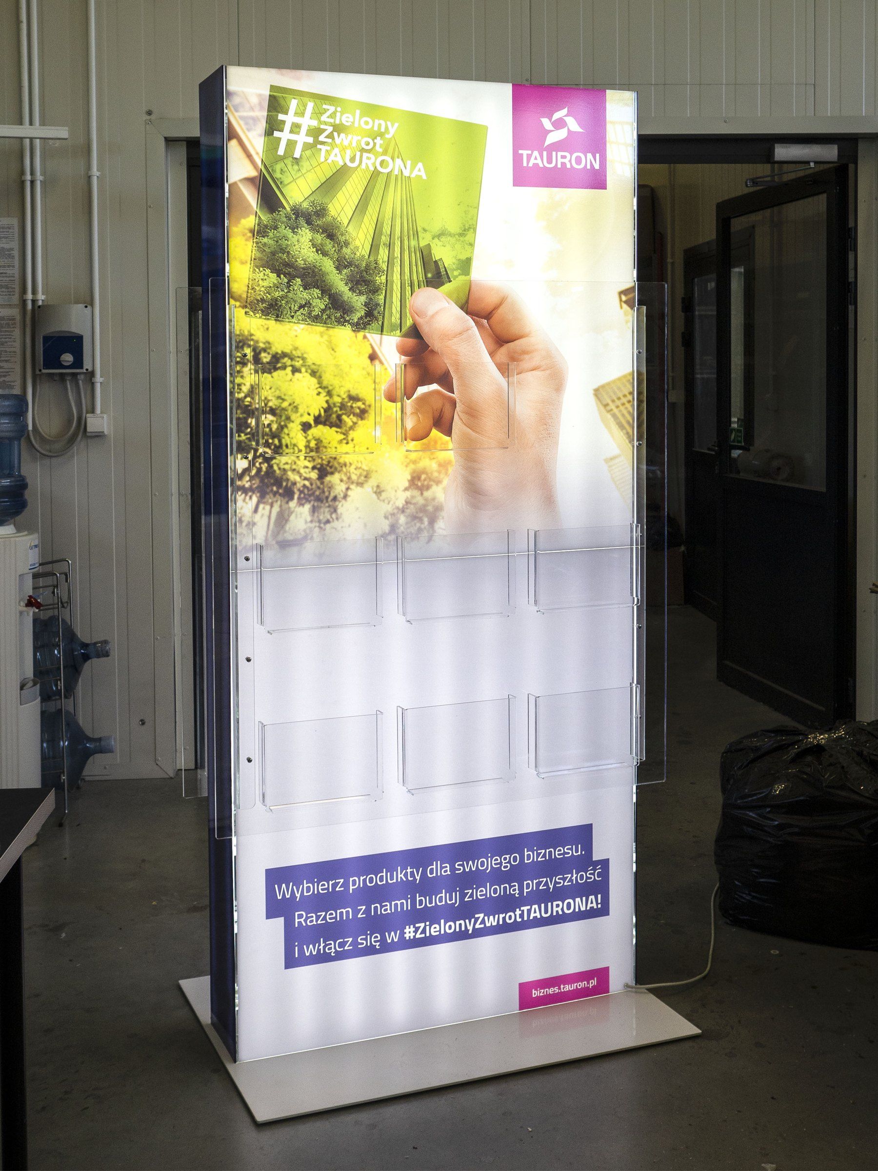 Podświetlany stand #ZielonyZwrotTAURONA z przezroczystymi kieszeniami z plexi na ulotki